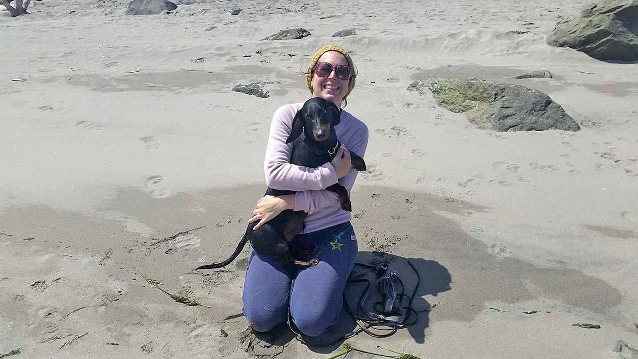 AHELP Project - Blog post, A Heartwarming Animal Hospice Tale from Wally, a 14-Year-Old Senior Dog by Christy Caplan, photo of Christy holding Wally on a sandy beach being in the moment.
