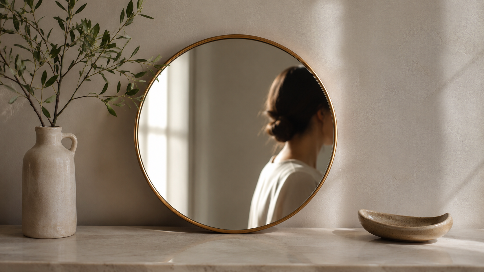 Woman reflected in a round mirror on a marble shelf, symbolising the mirror effect of seeing your own faults in others through self-reflection