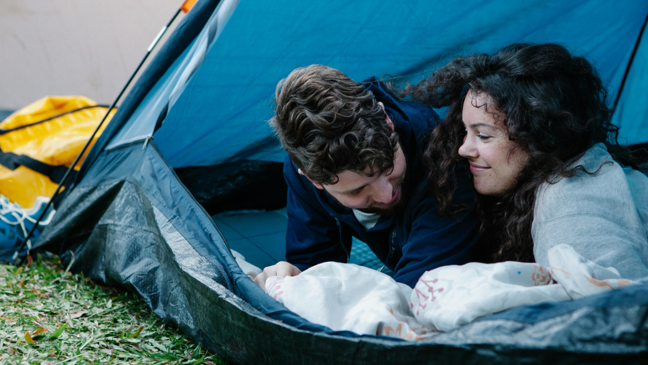 A couple in a tent, happy and reconnecting with each other, showing that reconnection after creating distance in a marriage is possible.