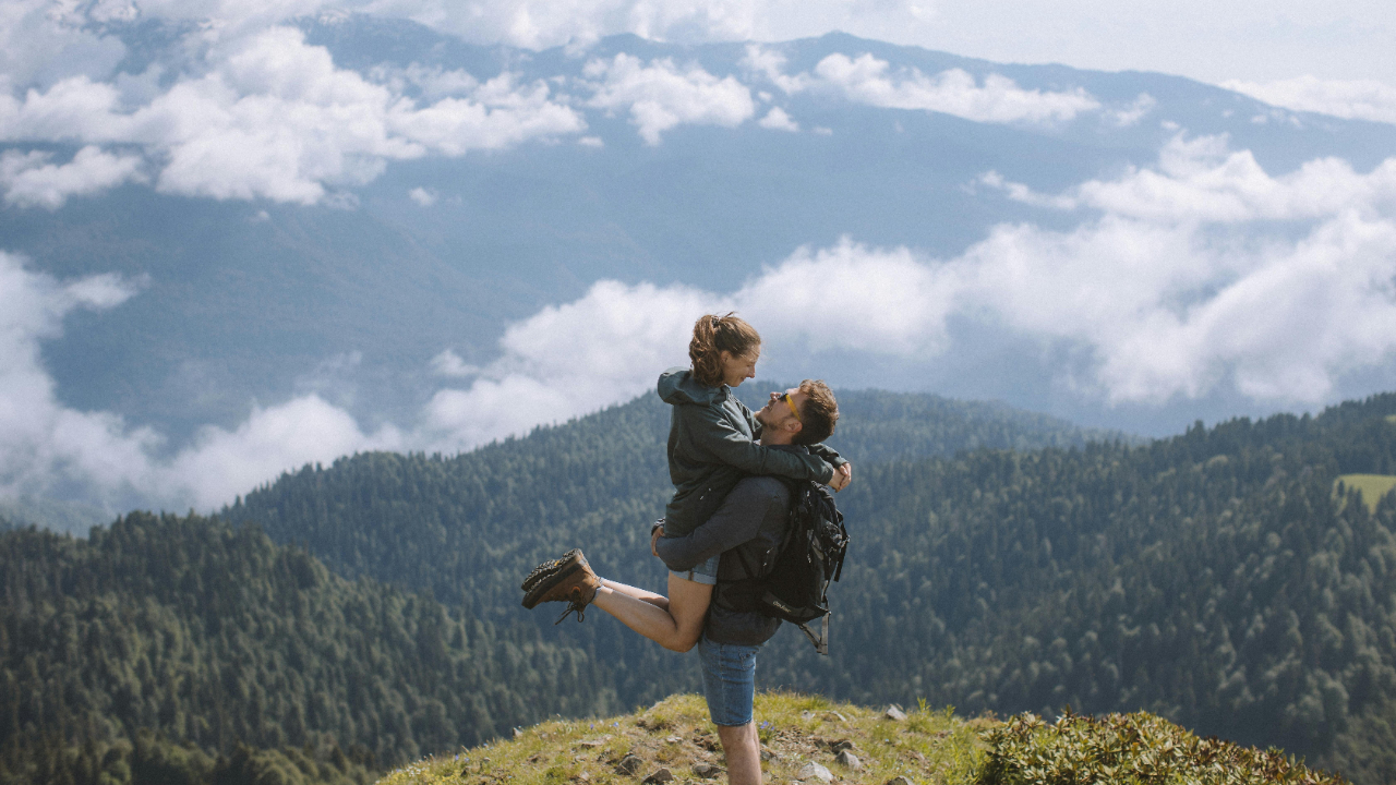 A man picks up his partner on a mountain, demonstrating joy and pleasure through playfulness, mirroring what is required of any relationship to ensure it lasts.