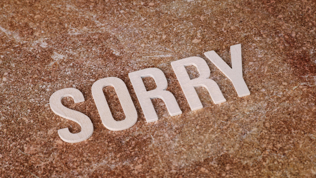 Block letters laid out on a concrete surface spelling out the word 'sorry'.