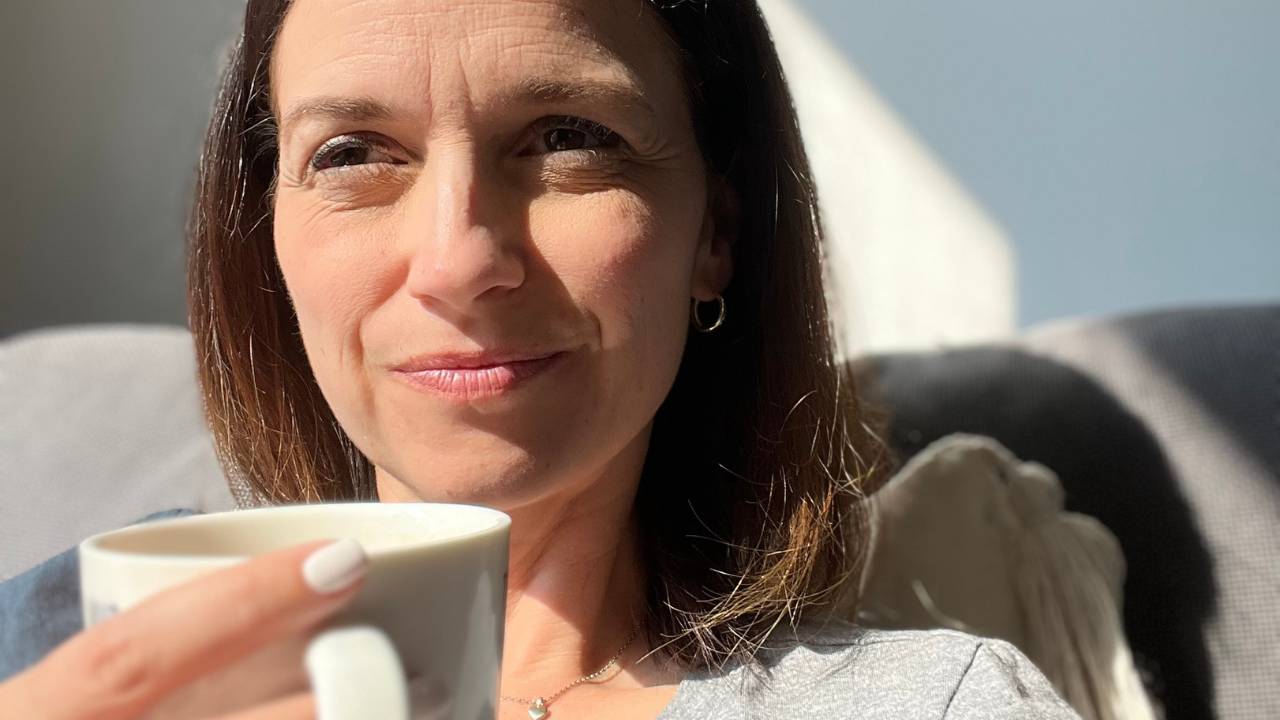 runner mom looking happy and proud sipping her coffee after her run. She is proud of the progress she has made going from not athletic growing up to a real runner now as an adult and mom