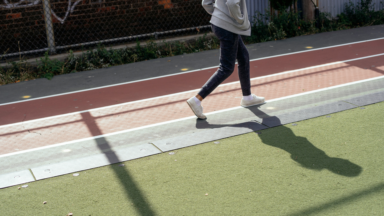 woman runner running on a track outdoors representing a minimal vialble run or a the idea of chunking down a run into smaller pieces to be able to get it completed.