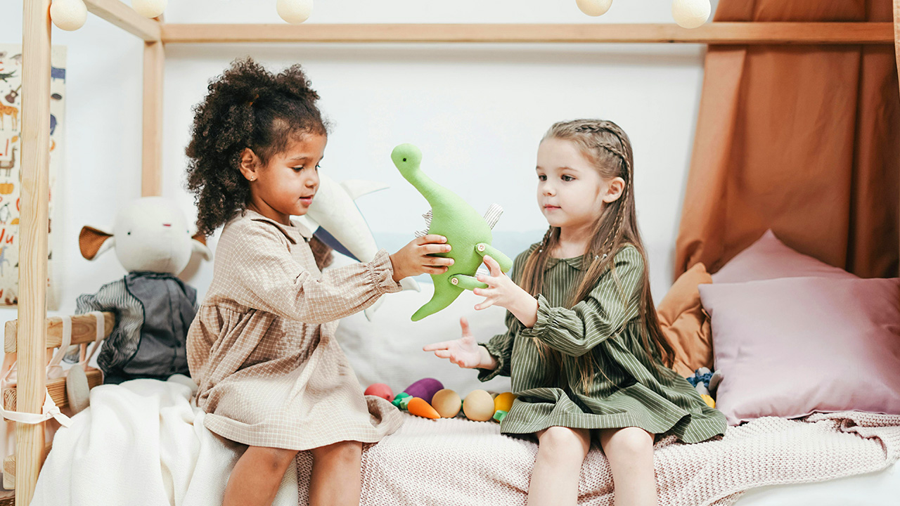 Two young girls sharing toys