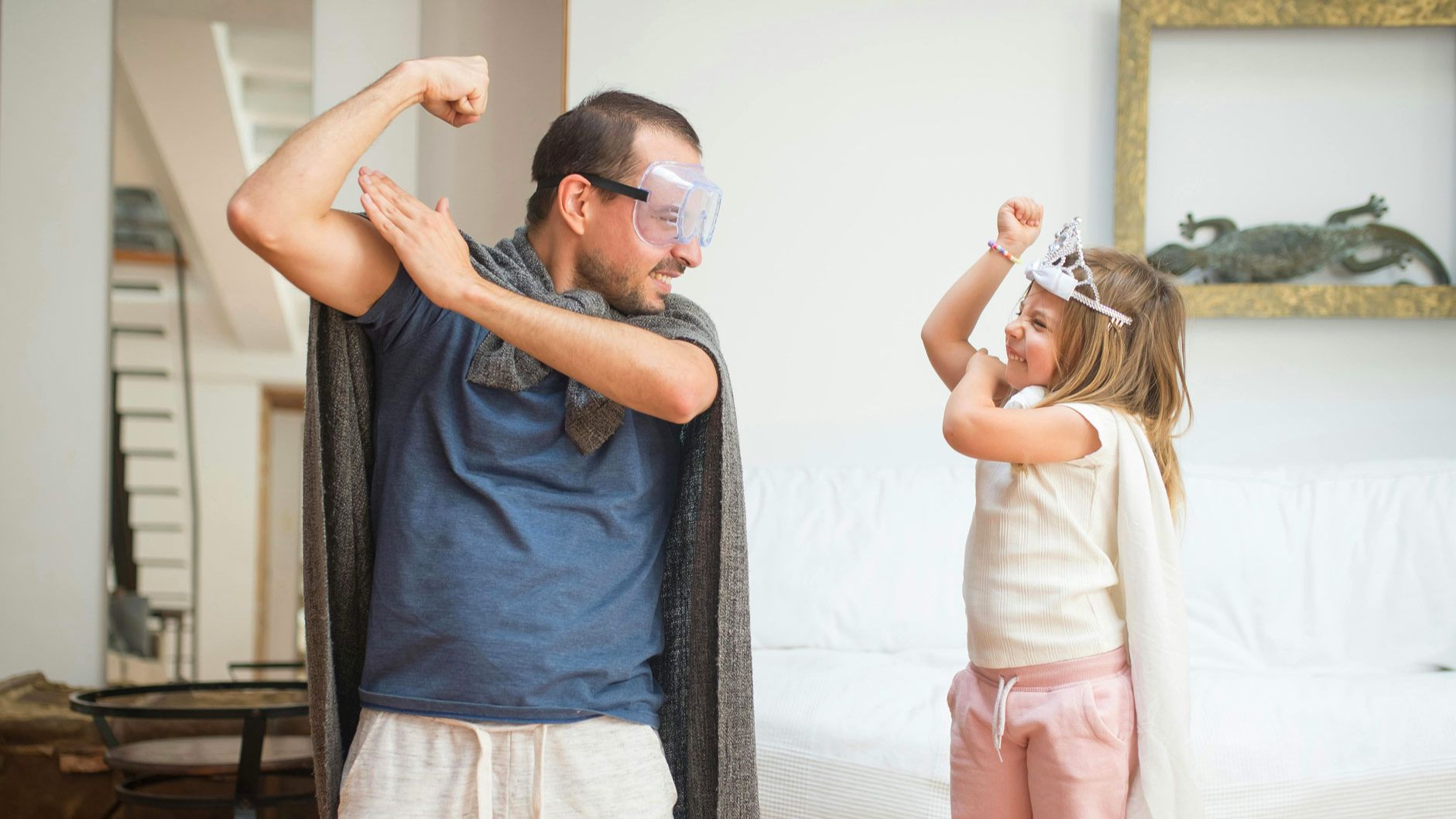 Father and daughter dressed as superheros and flexing their arm muscles