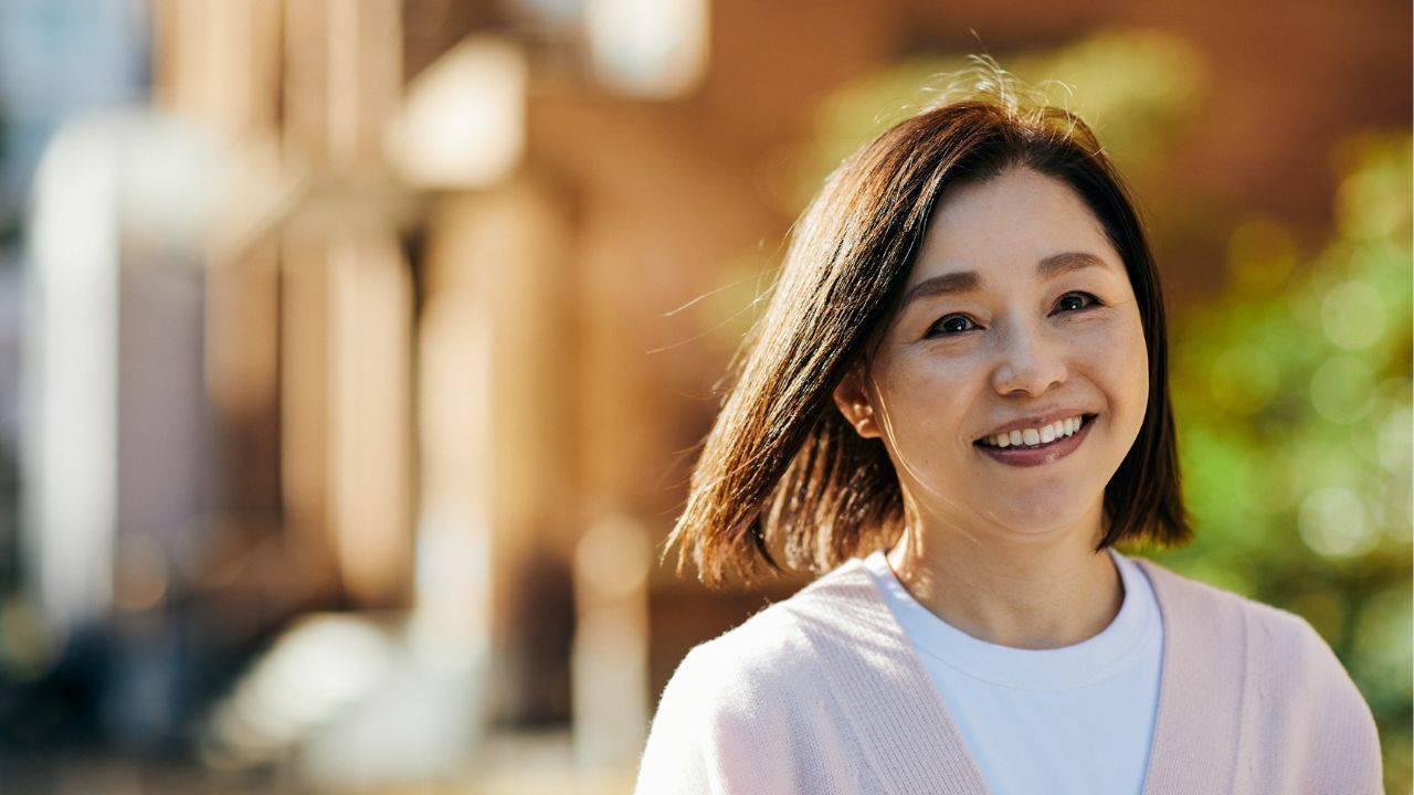 Smiling midlife woman standing outdoors in soft winter light, representing peace and confidence during the holiday season