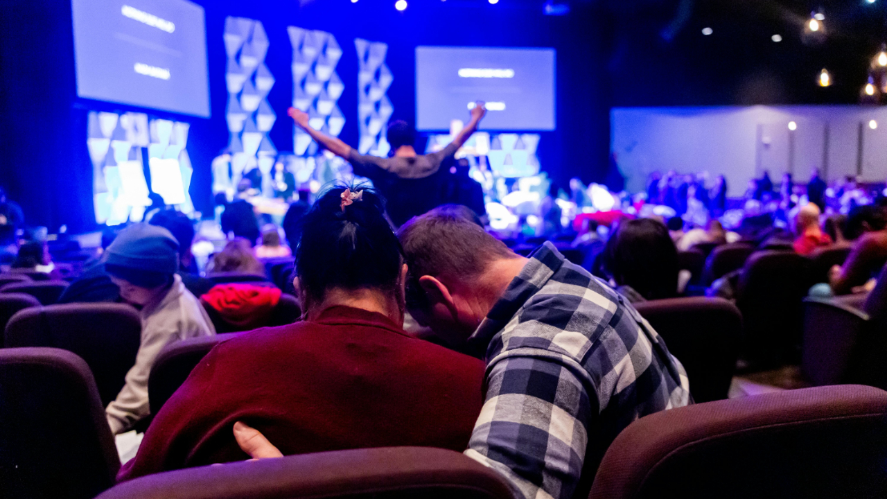 Modern church sanctuary with large LED wall displaying worship lyrics, worship team on stage, and congregation seated, featuring professional lighting, audio, and livestream setup
