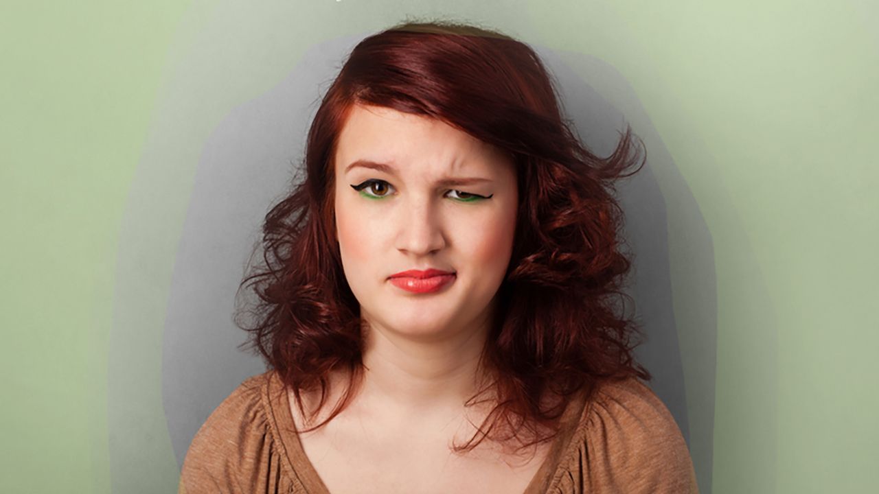 Portrait of a woman with a questioning expression against a soft background.