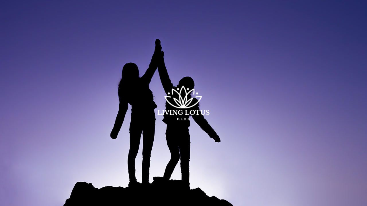 Two people on a hilltop holding hands high