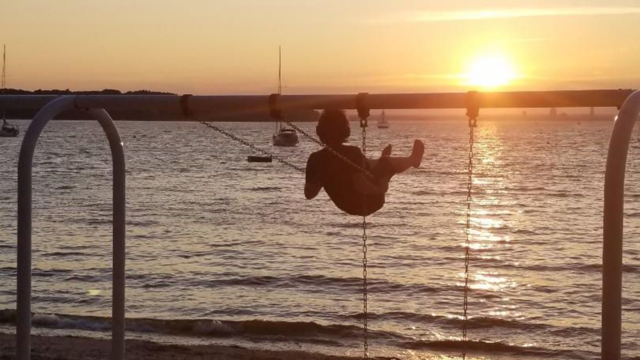 person on a swing set at sunset