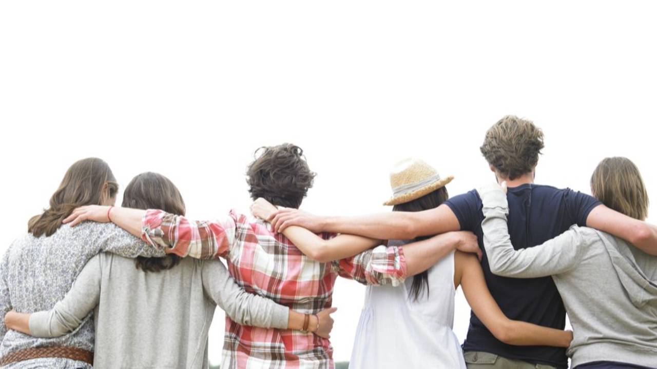 A group of students standing side by side with their arms around each other, symbolizing connection, support, and belonging in a learning community.