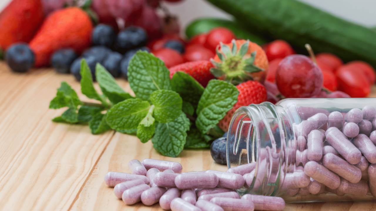 Flat lay of supplements, fresh greens, berries, and salmon, showcasing essential nutrients for optimal health and wellness.