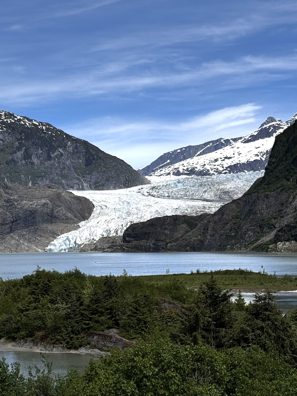 Mendenhall Glacier up close with blue sky and clouds, Mendenhall Lake and land in foreground