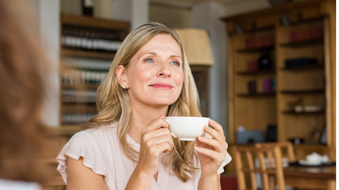 Woman over 50 smiling drinking tea with self-care