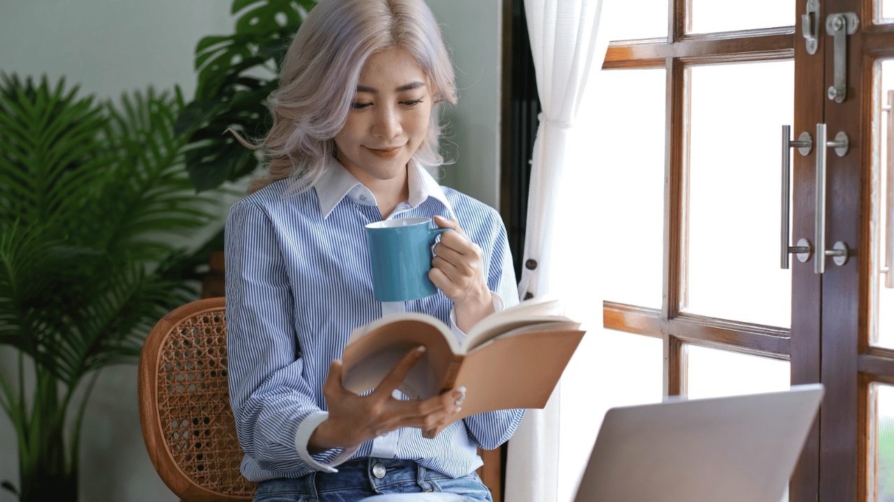 Asian woman reading a book and drinking coffee in the morning.