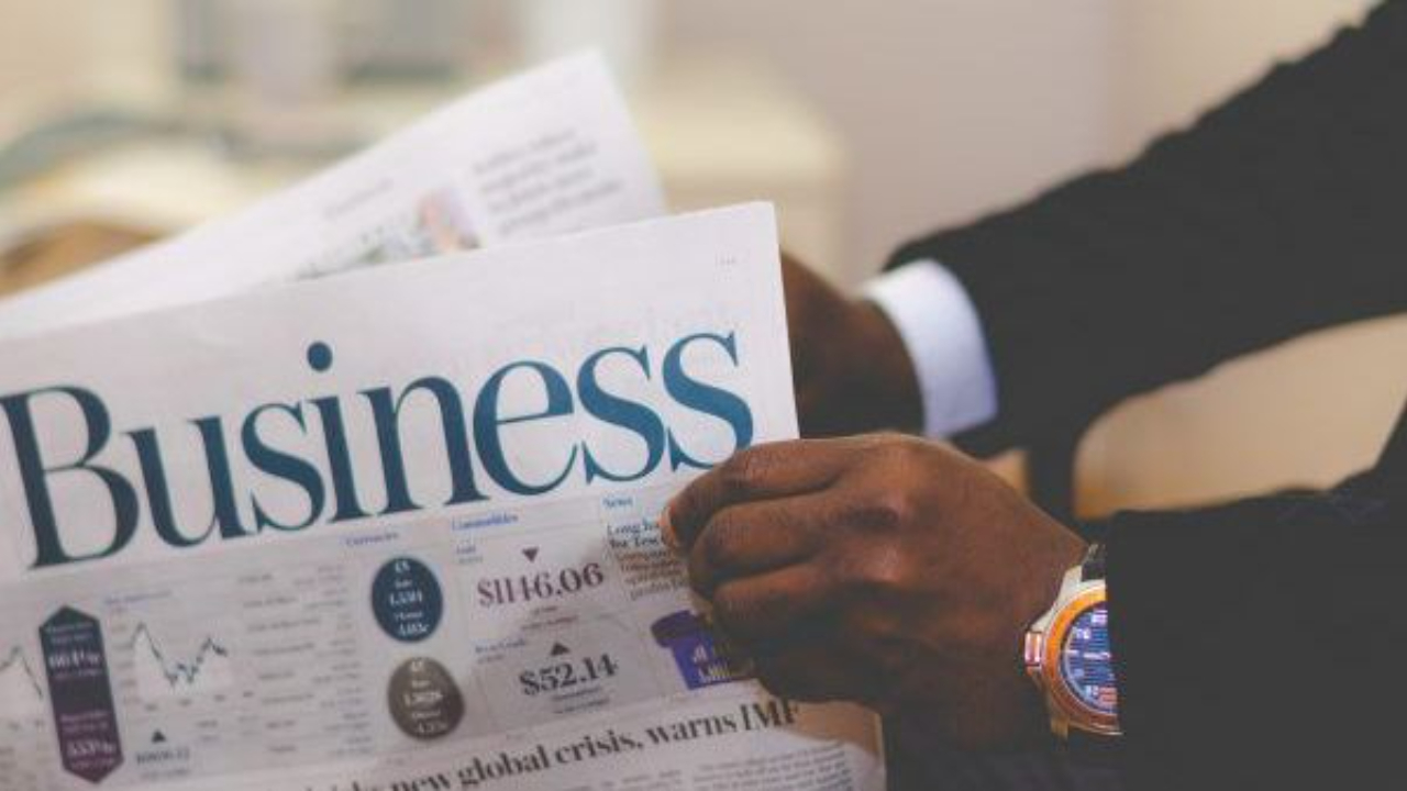 A person reads a 'Business' newspaper, subtly hinting at financial topics and the stress often associated with money management and economic news