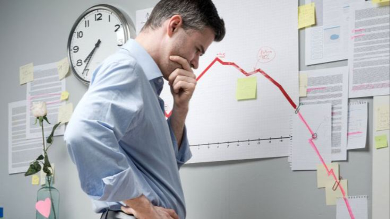 A worried entrepreneur or businessman looking at a downward-trending red financial chart on a wall, symbolizing business failure, financial chaos, or a struggling business struggling to scale.