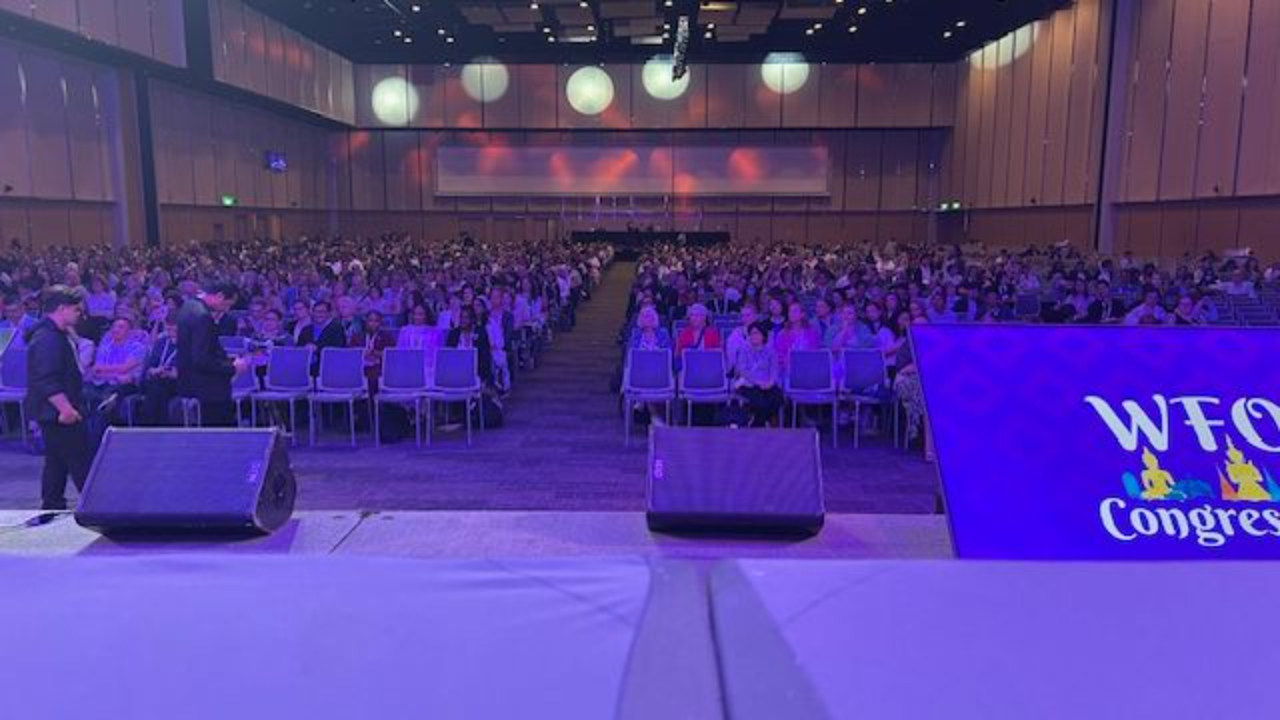 The view from the stage at the WFOT Congress 2026, looking out over the crowd bathed in purple lighting reflecting off the stage.