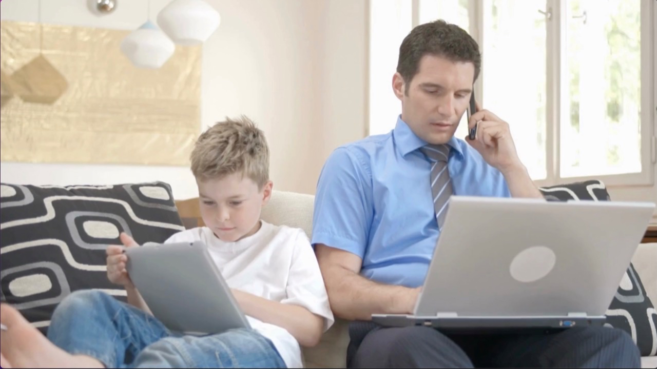 Dad and son, both looking at screens