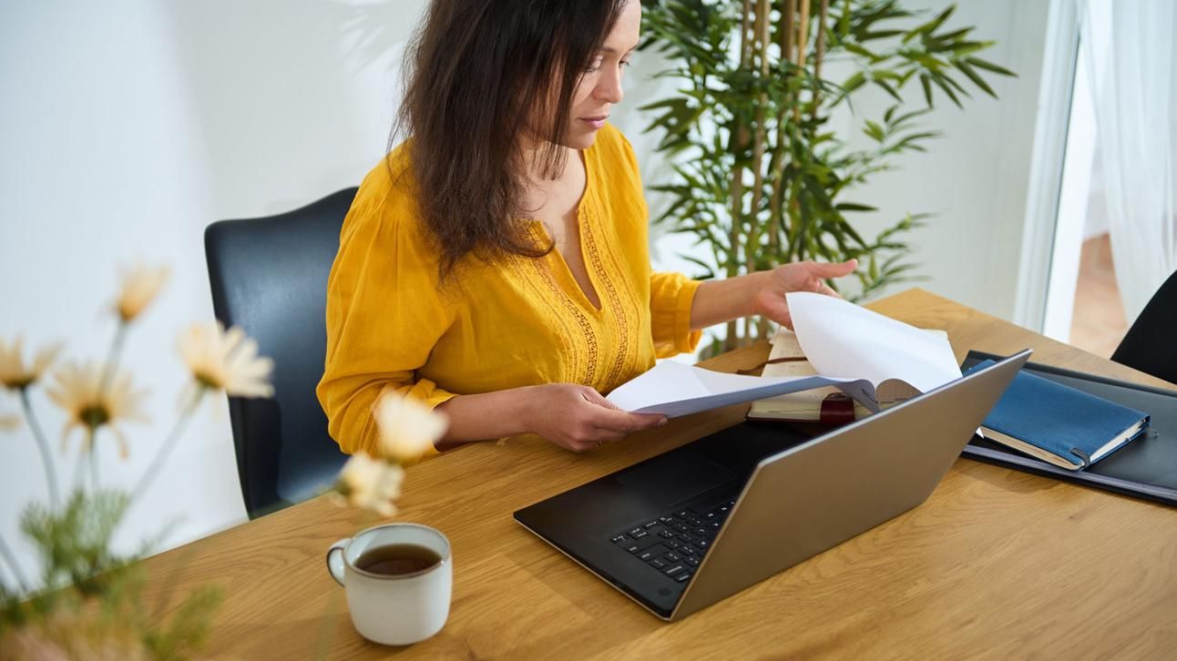 A professional woman working at her laptop in an organized home office, confidently managing her virtual assistant business.