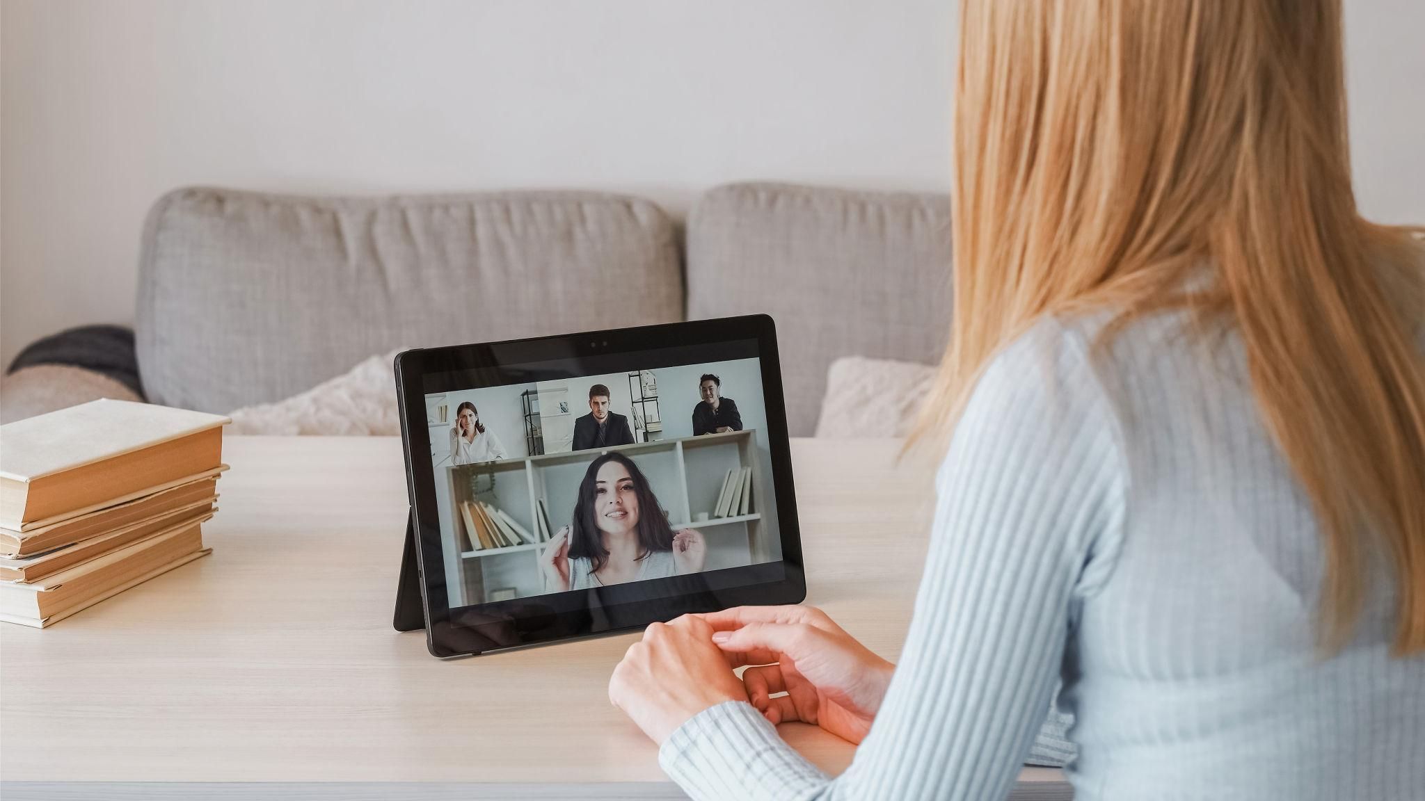 A business woman smiling during a Zoom call on her laptop, having a professional virtual meeting with a client in a home office setting.