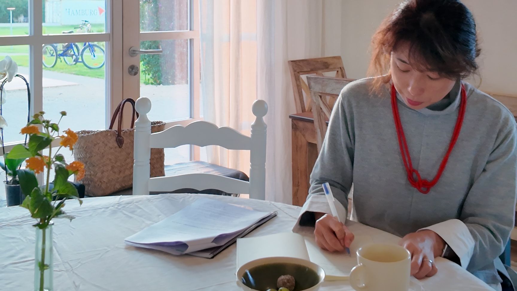 Maika is journaling on a notebook with a cup of tea