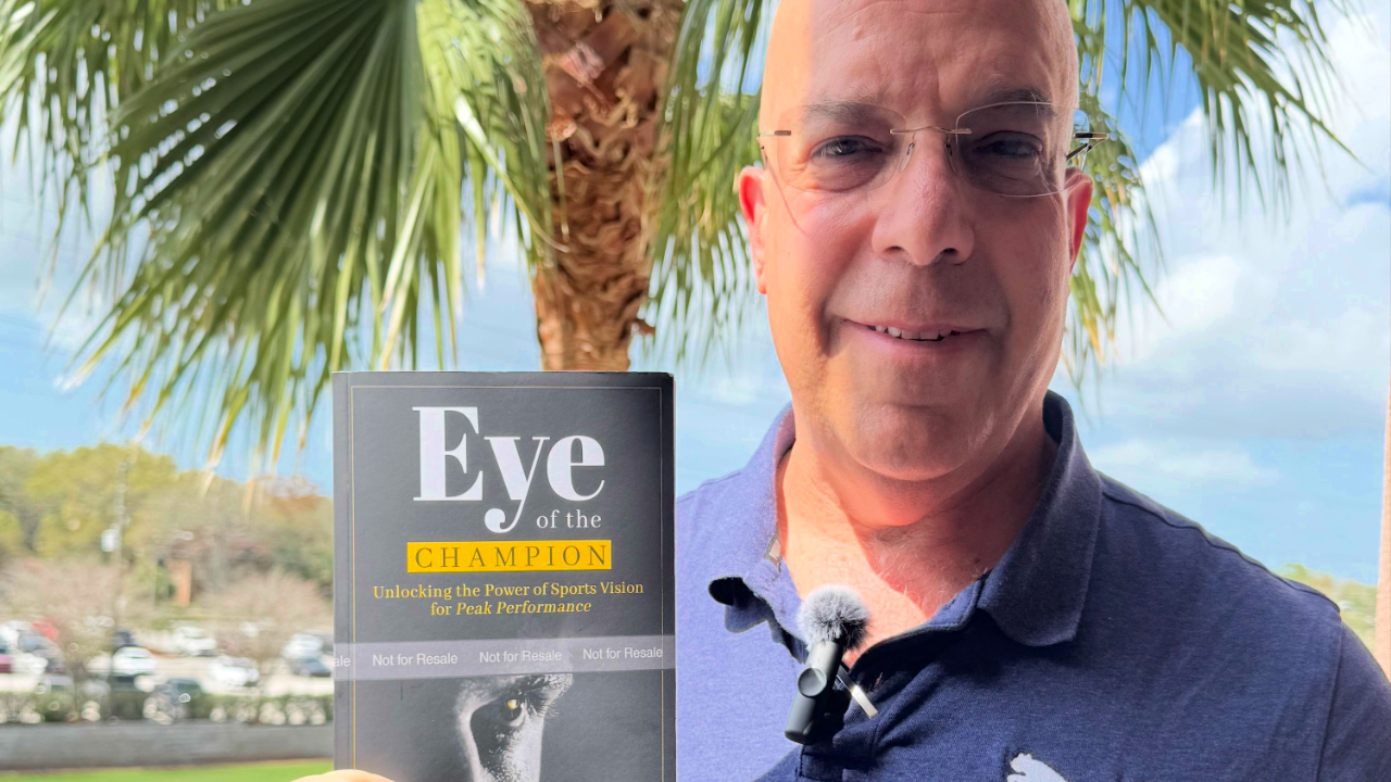 Dr Laby holding the book "Eye of the Champion"