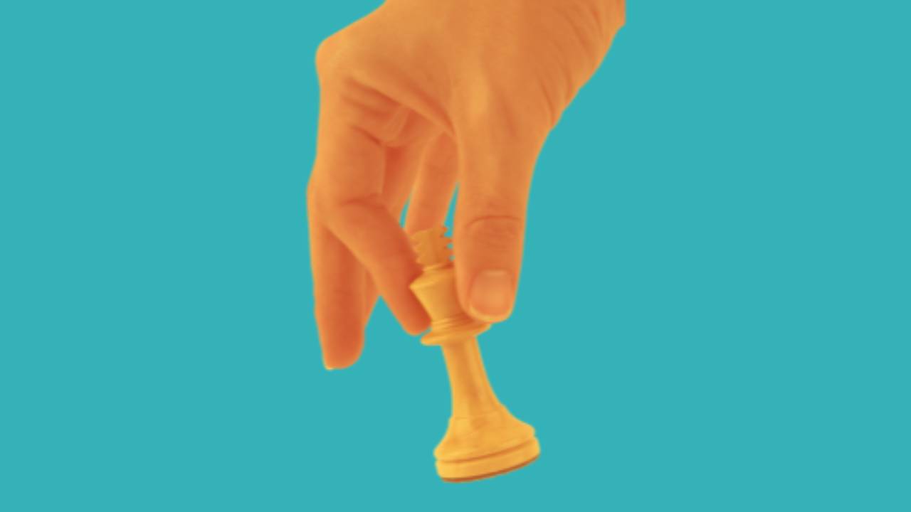 Mans hand holding a chess piece