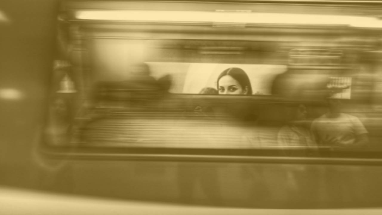Image of a woman looking through the window of a fast moving subway car