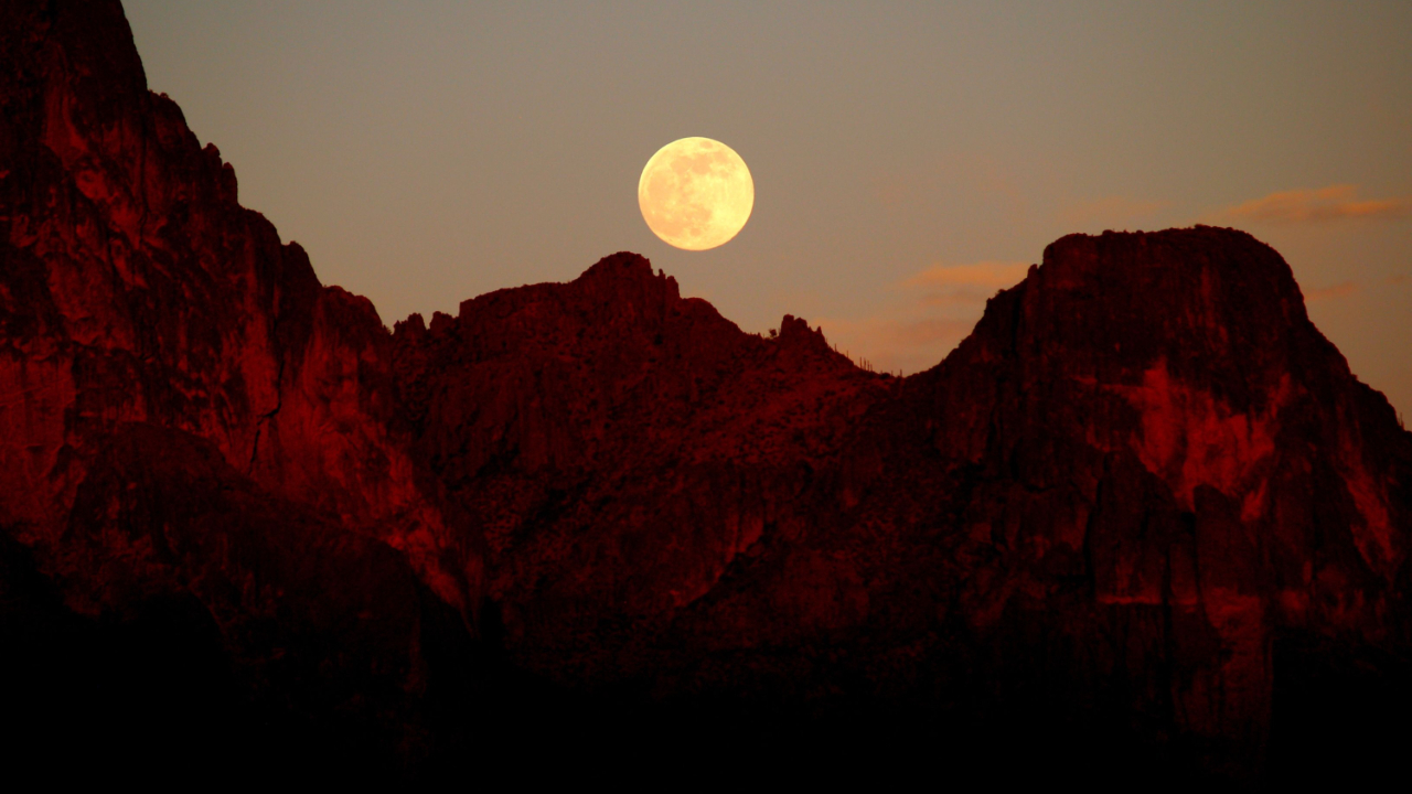 Moon rising over atmospheric red mountaints