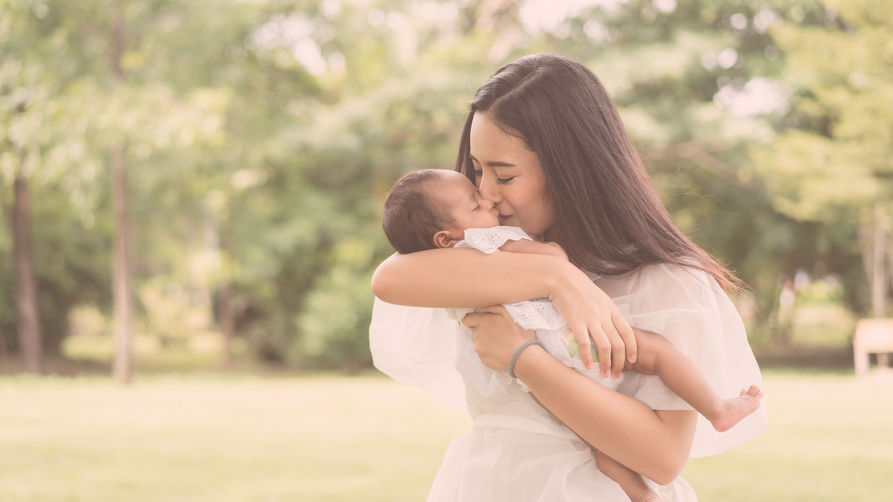 a mother holding a baby and kissing its cheek