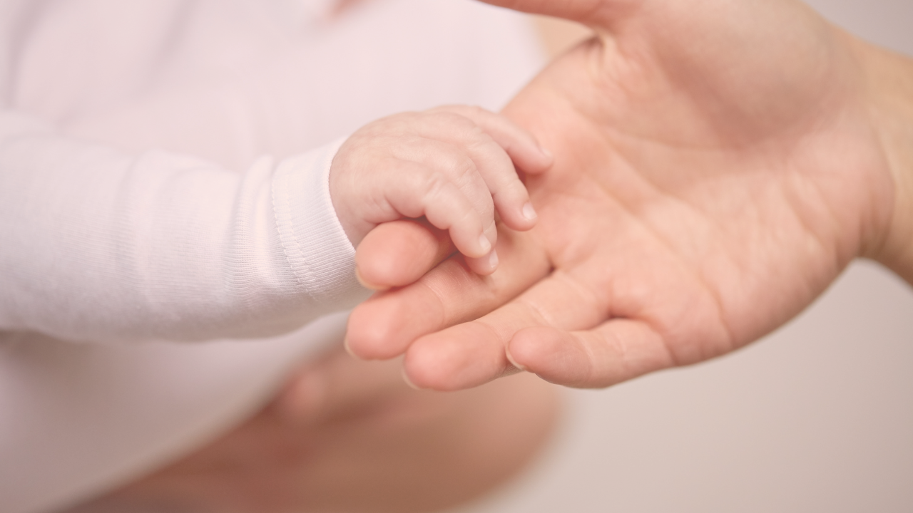 a baby holding on to a mothers finger