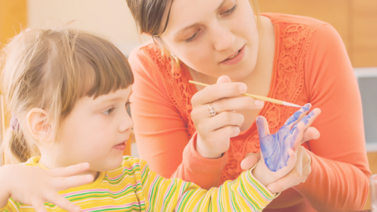 A babysitter painting a childs hand blue