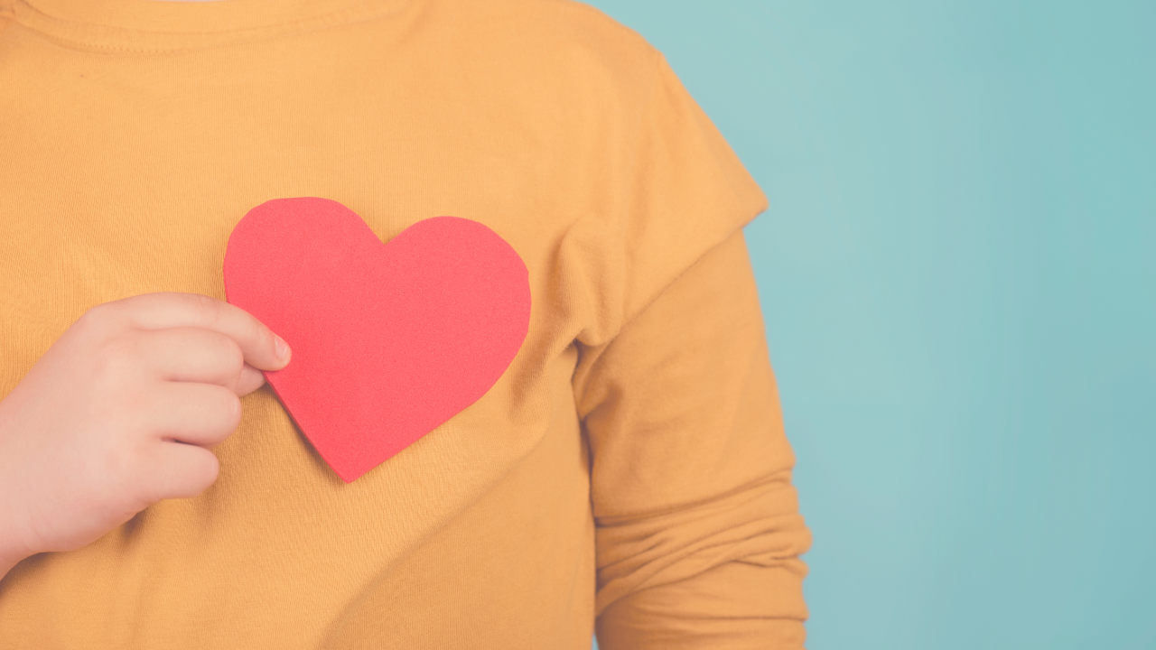 a kid holding a paper heart over his heart