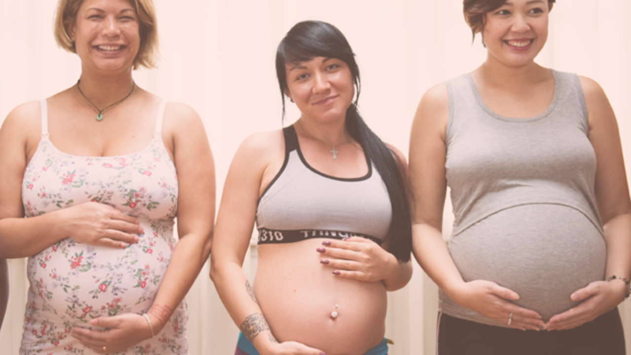 Three smiling pregnant women standing beside one another
