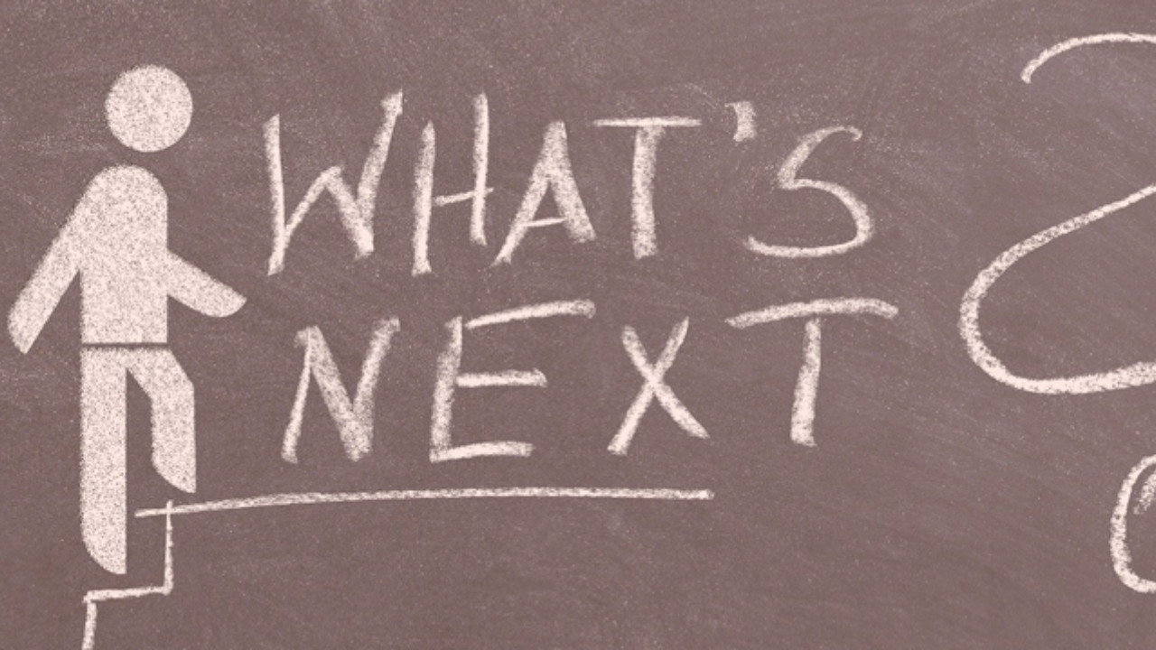 A chalkboard with writing that says "what next?"