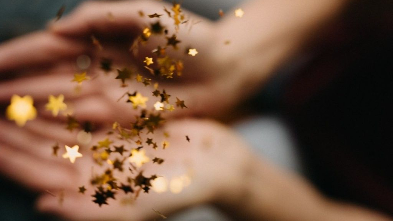 Coach voor vrouwen Esther van Hemert laat gouden sterren los uit haar handen. Een krachtig beeld van vrijheid, lichtheid en bruisende levensenergie.