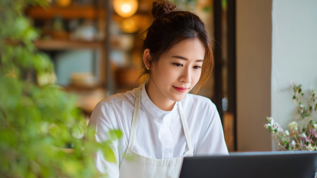 Junge Mitarbeitende lernt am Laptop in einem modernen Arbeitsumfeld. Die Szene zeigt digitale Weiterbildung in der Gastronomie und verdeutlicht, wie Online-Kurse Mitarbeitende flexibel und praxisnah schulen.