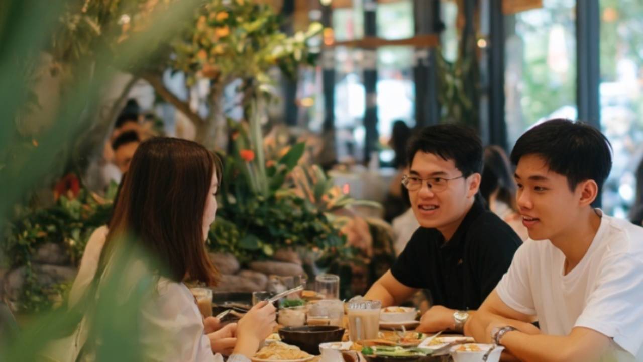 Gäste sitzen in einem modernen Restaurant und genießen ihr Essen, während gut geschulte Mitarbeitende für einen reibungslosen Ablauf sorgen. Szene aus der Gastronomie, die den Einfluss von Weiterbildung und professioneller Schulung im Service zeigt.