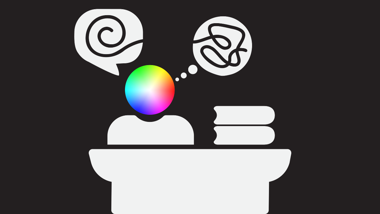 A person at a desk with piles of files on it. The person has a spectrum coloured head, with a speech bubble with a curved spiral line representing speech, but a thought bubble with a squiggled line to show they are pretending to be ok