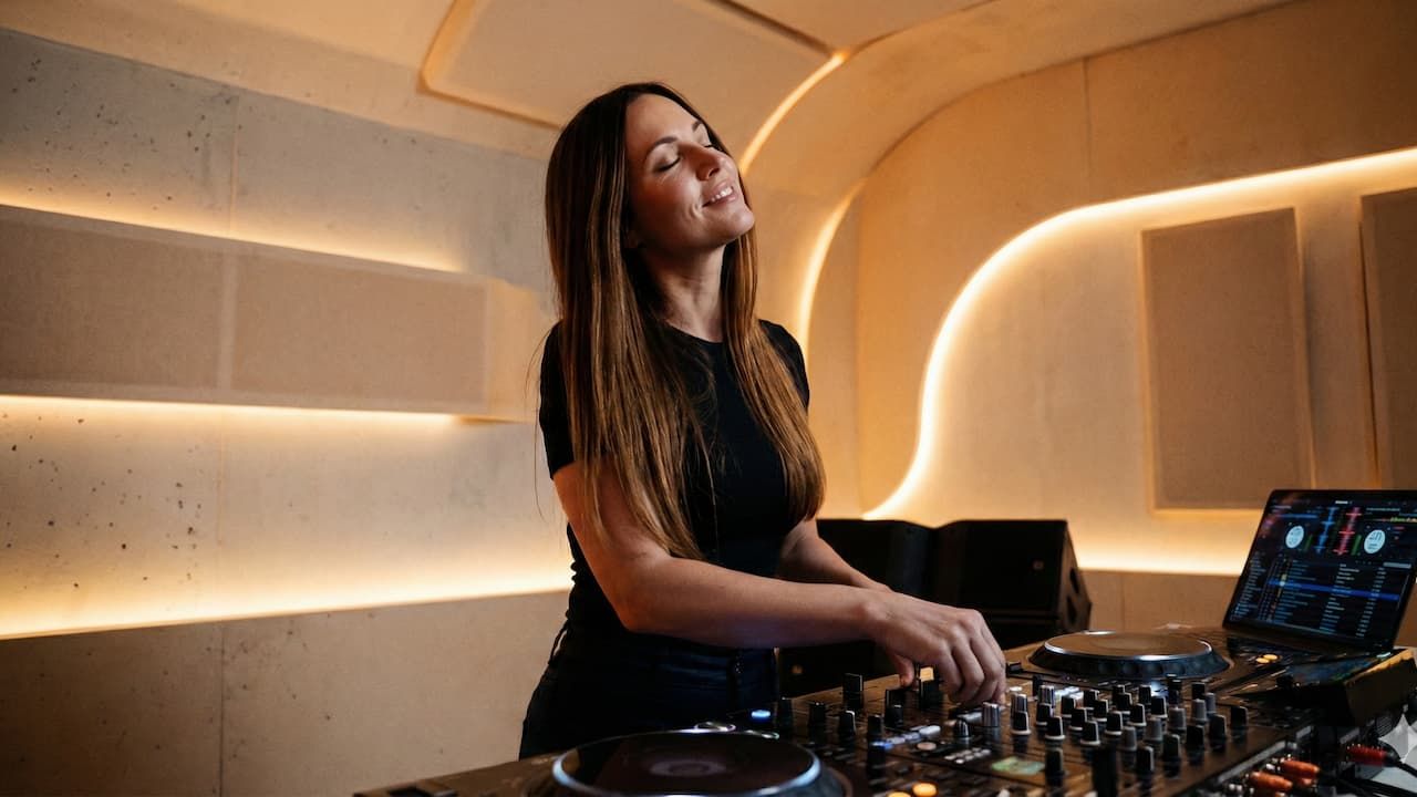 Mujer pinchando en una cabina sintiendo la música