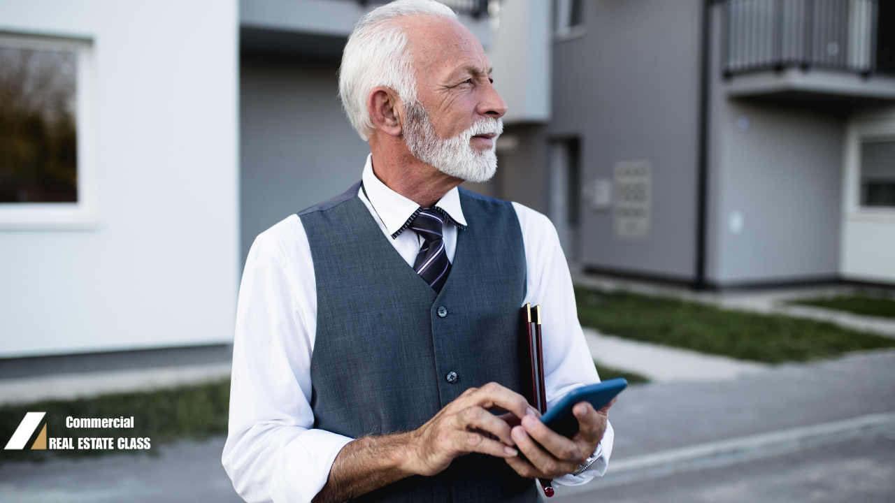 Experienced commercial real estate investor reviewing property details on a smartphone outside an apartment building