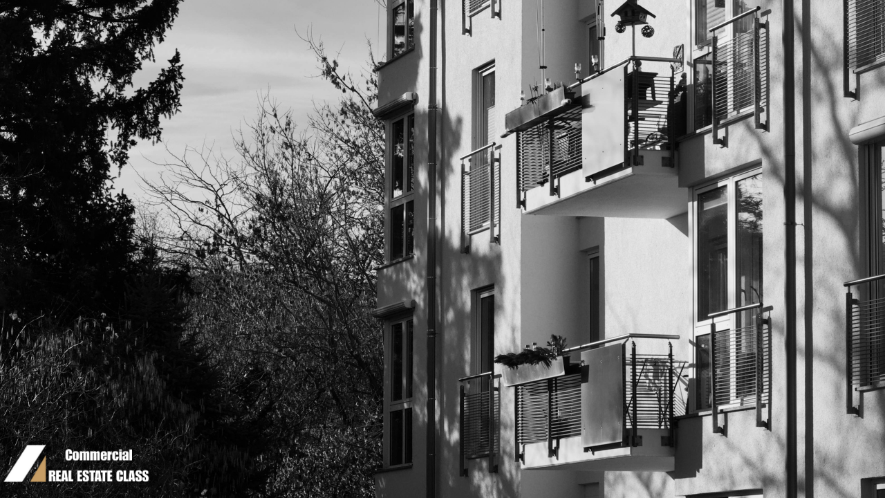 Black and white image of a multi-unit apartment building with shadows creating a subtle, eerie atmosphere representing hidden risks in commercial real estate