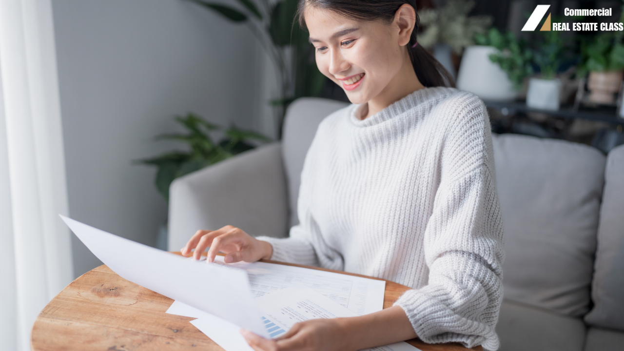 Commercial real estate investor reviewing financial reports and property income statements while analyzing a potential commercial property investment deal.