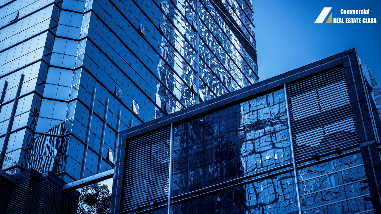 Modern glass commercial office building reflecting surrounding skyline, representing income-producing commercial real estate and property valuation based on net operating income and cap rate analysis.
