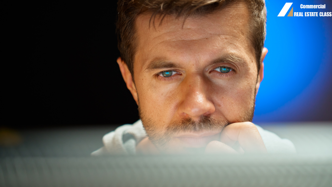 Commercial real estate investor studying property details on a computer with a focused, concerned expression while evaluating potential risks before purchase