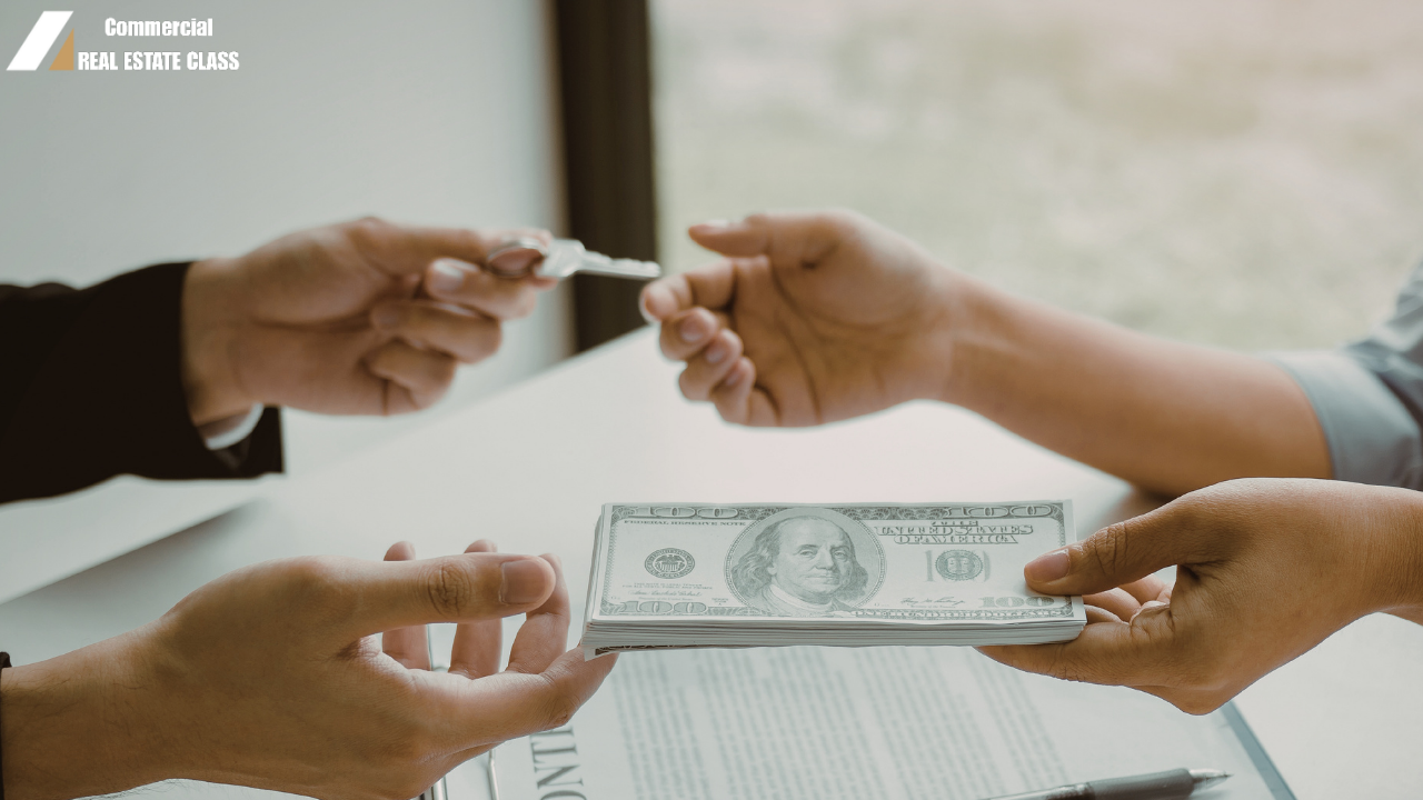 Hands exchanging keys and cash over a signed document representing a commercial real estate investment transaction