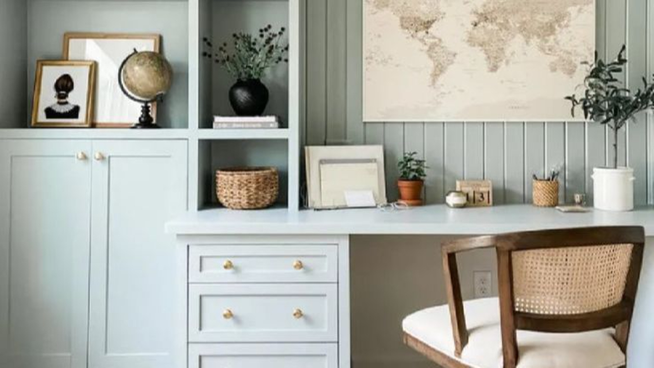 Home office featuring built-in cabinetry painted in Benjamin Moore Boothbay Gray, with brass hardware, natural wood accents, and layered decorative accessories in a soft, coastal palette.