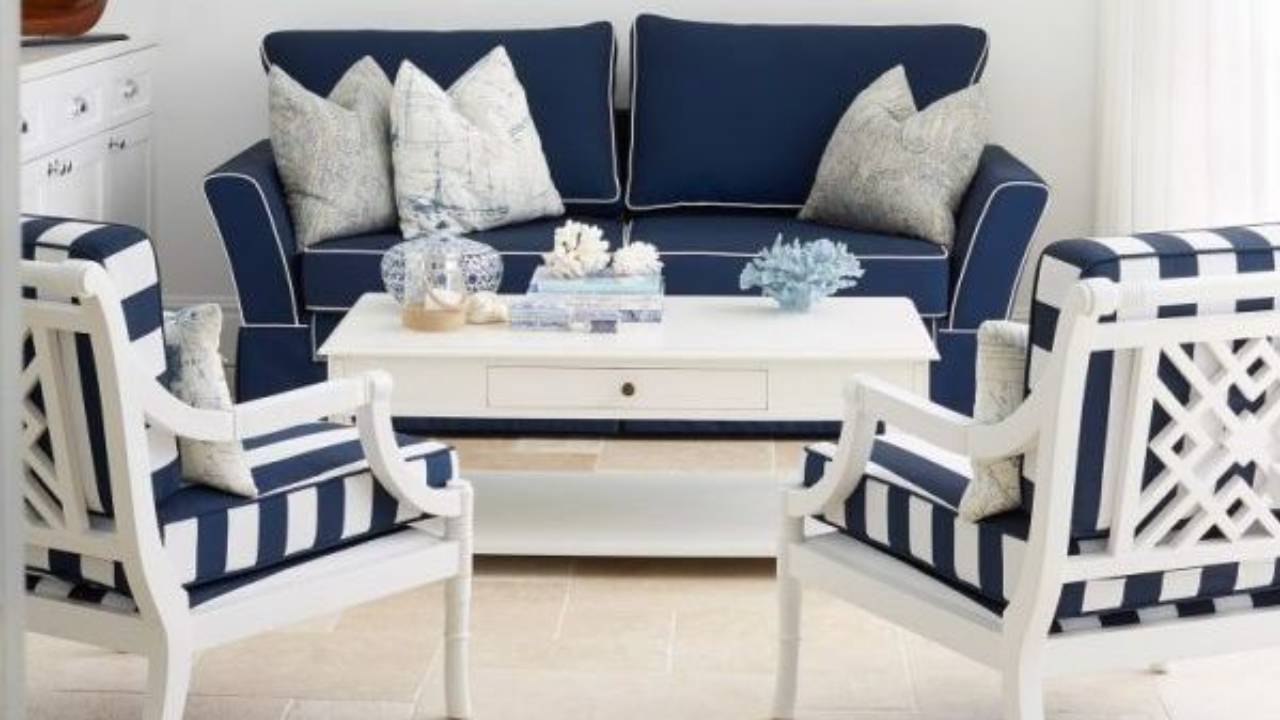 Elegant Hamptons-style living room featuring navy blue sofa, striped armchairs, crisp white furniture, and coastal-inspired decor.