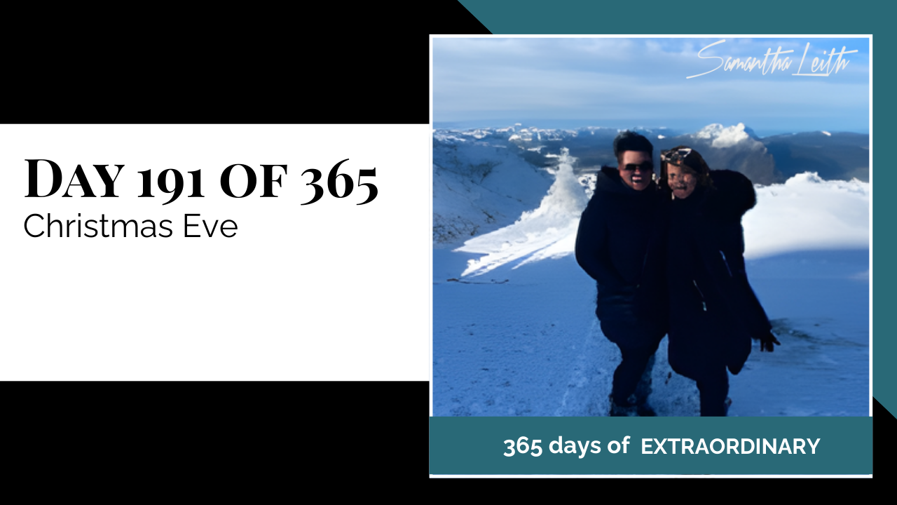 A close-up outdoor selfie of two women in thick winter gear standing in a mountainous, snow-covered landscape, used to illustrate a blog post about spending Christmas Eve away from home, winter holiday travel, and enjoying a cold-weather destination.